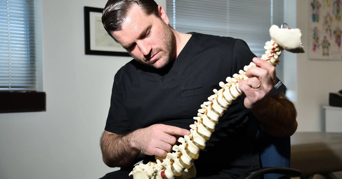 Chiropractor at Maryland Chiropractic & Physical Medicine in Edgewater, MD, pointing to the lower lumbar spine on an anatomical spine model